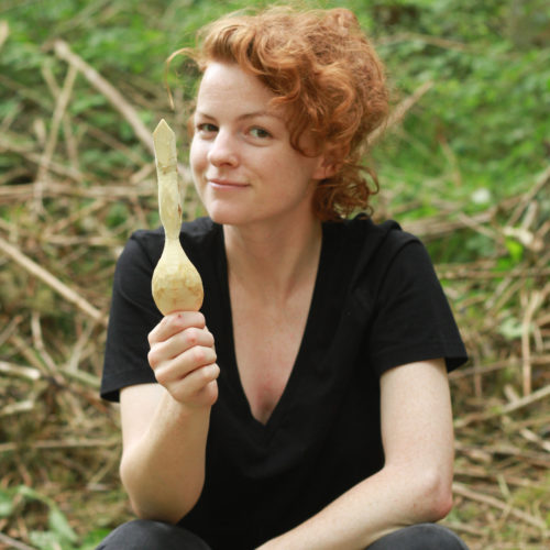 A student showing the spoon tha they have carved on the course