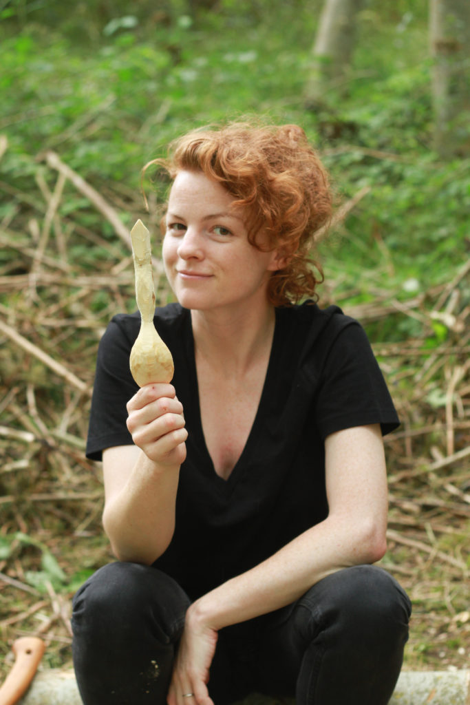 A student showing the spoon tha they have carved on the course