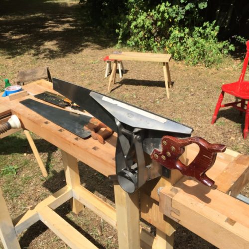 a saw in a saw vice attached to a bench outside