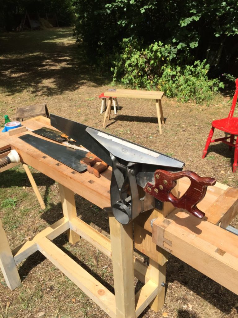 a saw in a saw vice attached to a bench outside
